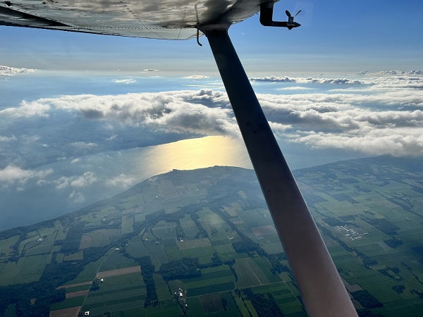 picture looking out of plane above clouds over the finger lakes